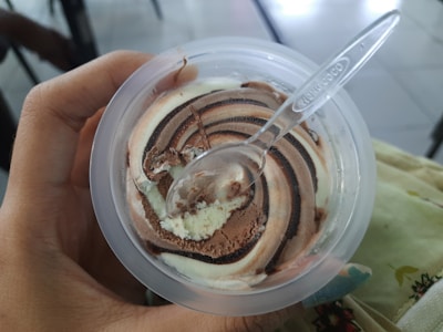a person holding a plastic container with ice cream in it