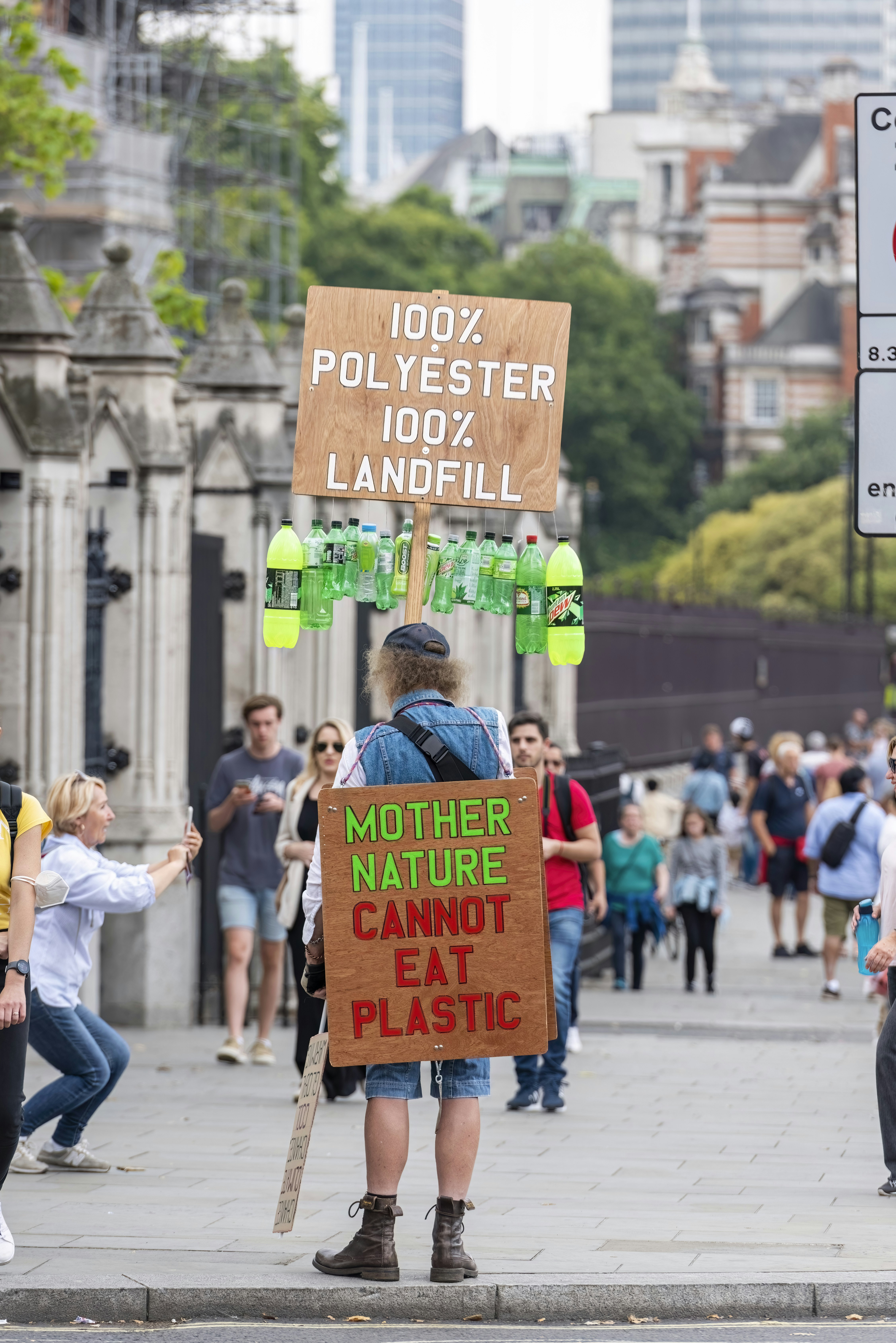 a man holding a sign that says mother nature cannot eat plastic