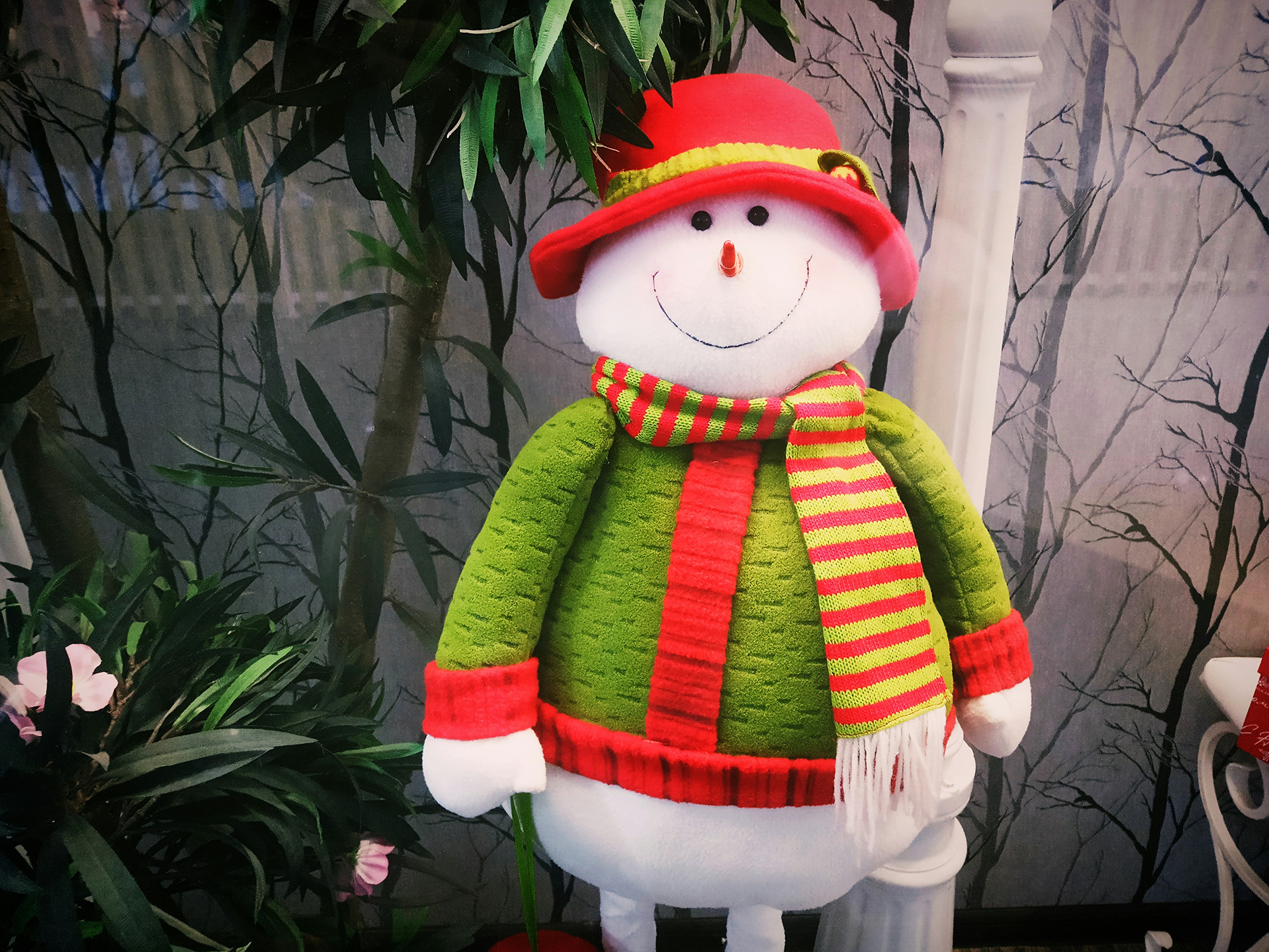 ein Schneemann mit roter Mütze und grünem Schal