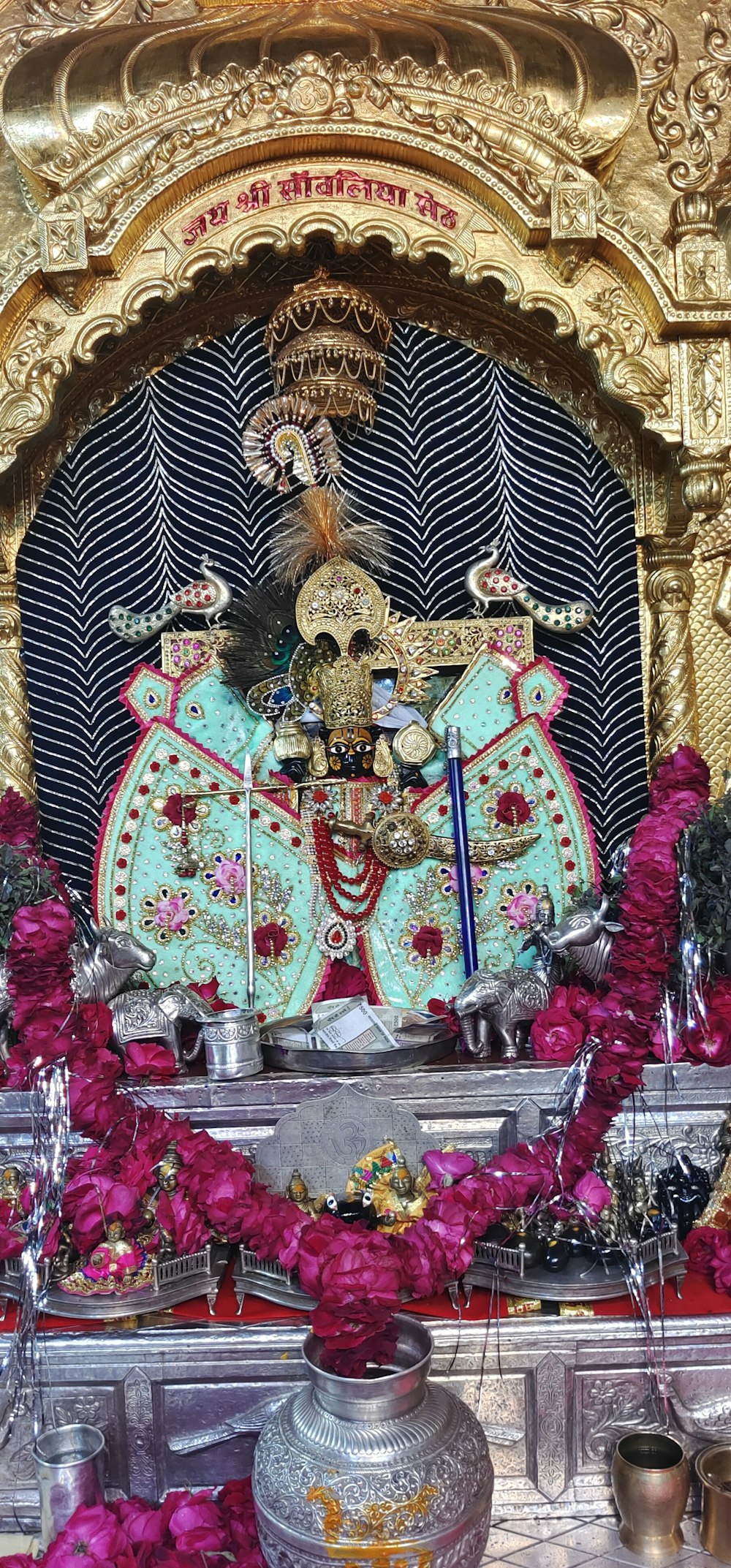 a statue of a person sitting on a throne surrounded by flowers