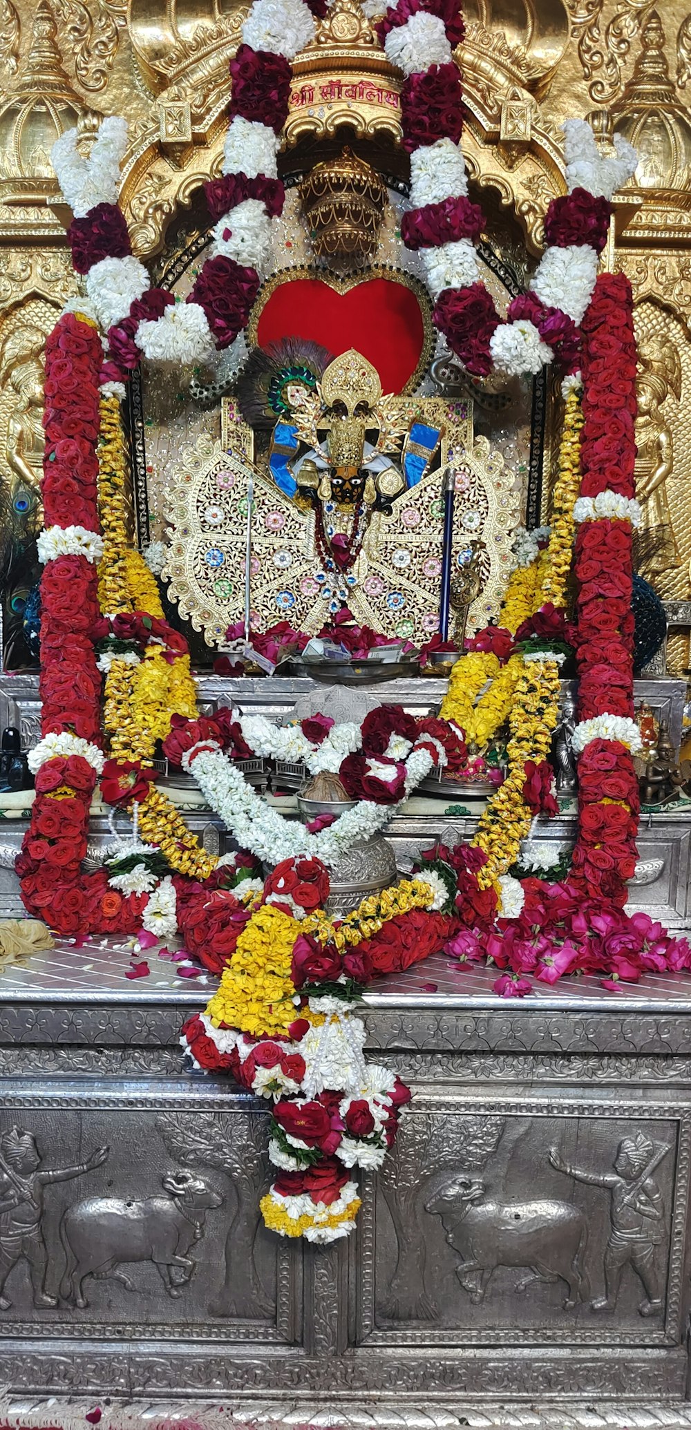 a shrine with flowers and a statue in the background