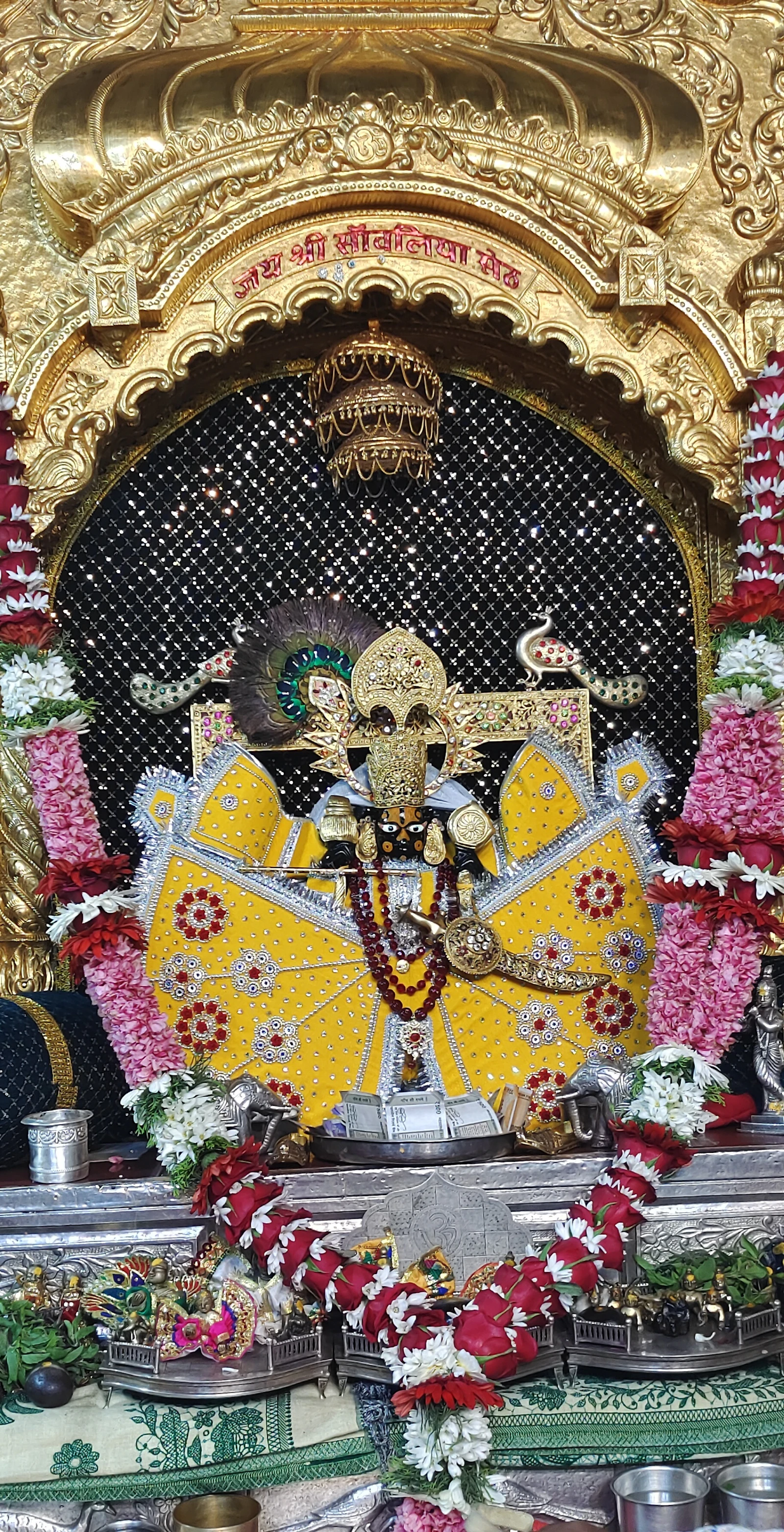 Ornate golden temple shrine of a Hindu deity decorated with flowers