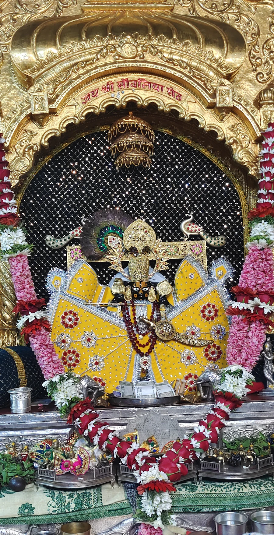 Ornate golden temple shrine of a Hindu deity decorated with flowers