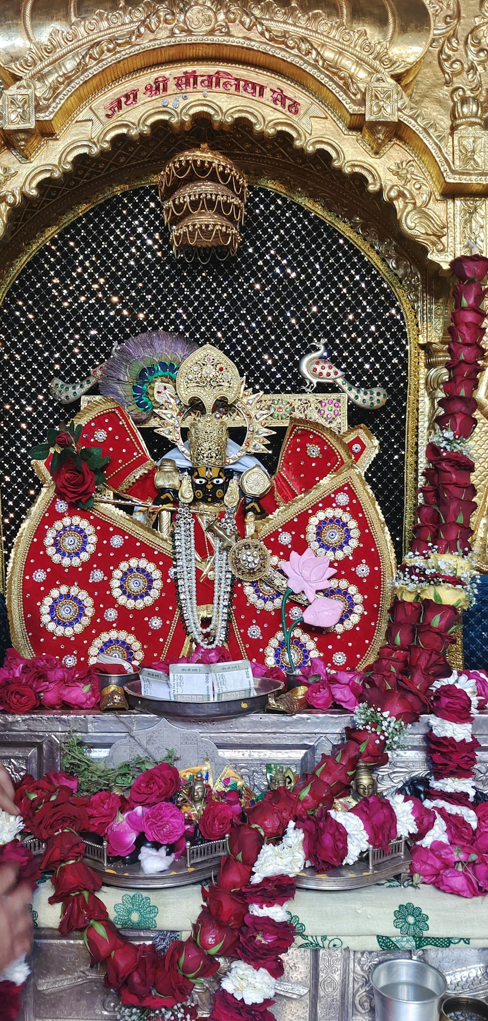 a shrine with a statue of a god surrounded by flowers