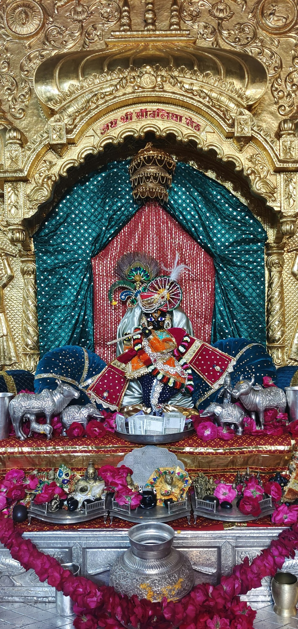 a shrine with a statue of a god surrounded by flowers