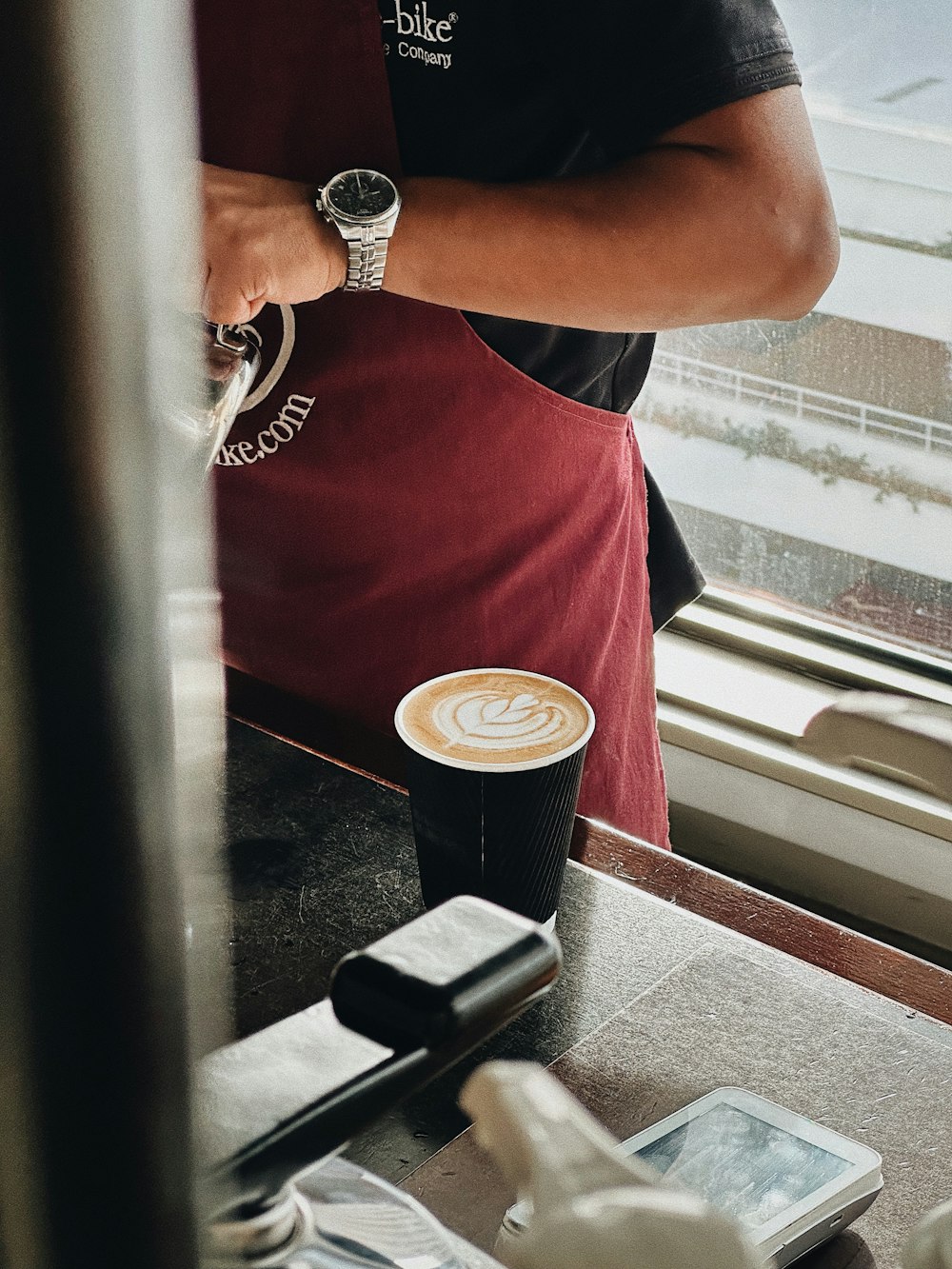 a man standing in front of a window next to a cup of coffee