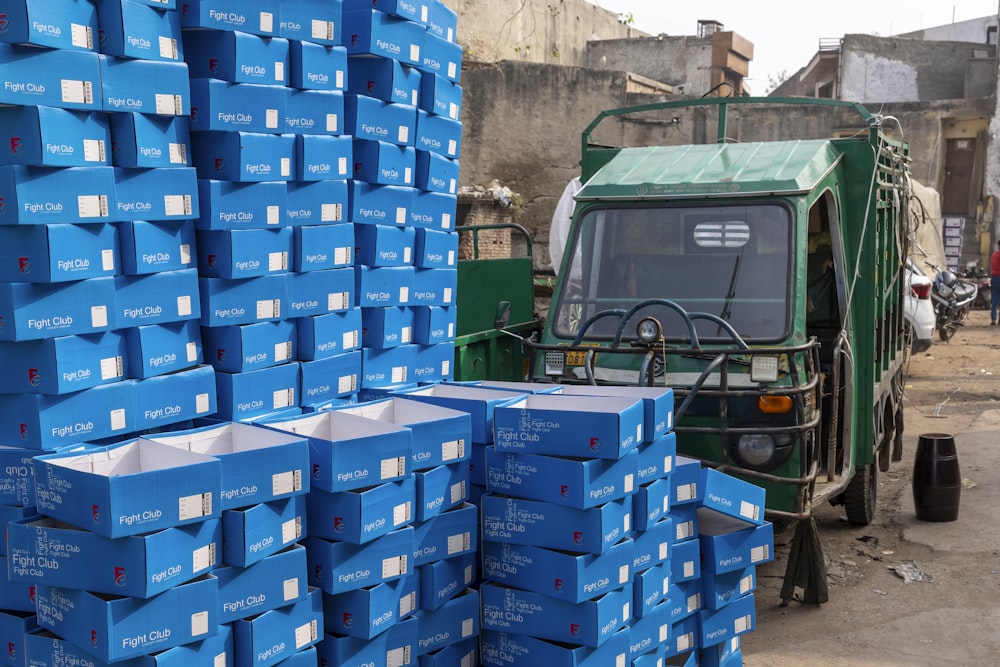 a green truck parked next to a pile of blue boxes