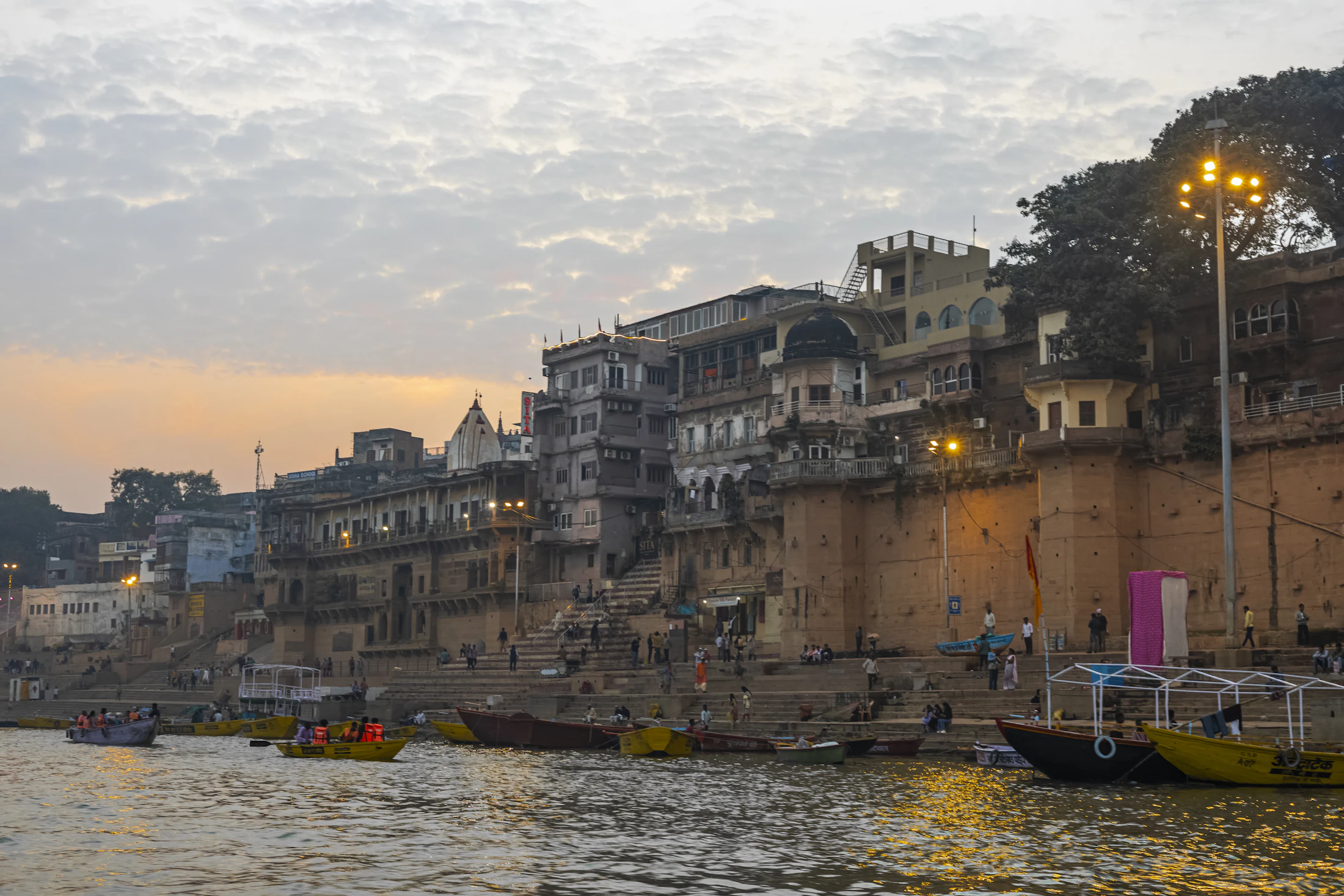 Wooden boats clustered on the Ganga below the ghats of Varanasi at dusk
