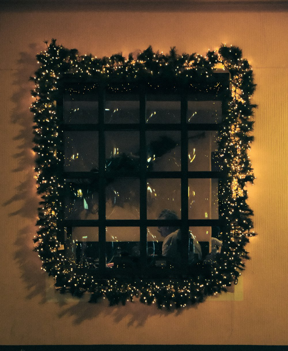 a window decorated with christmas lights and greenery