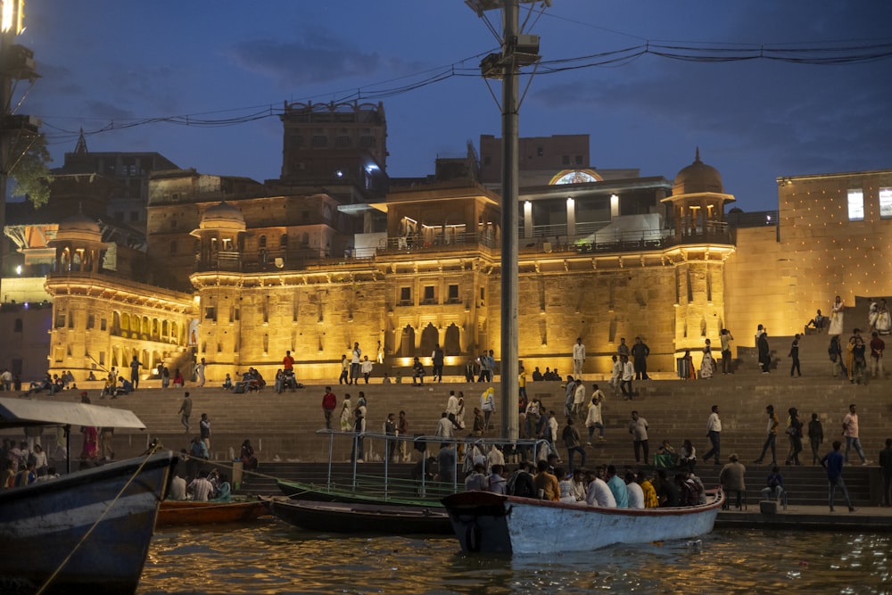 a group of people standing on the side of a river next to a building