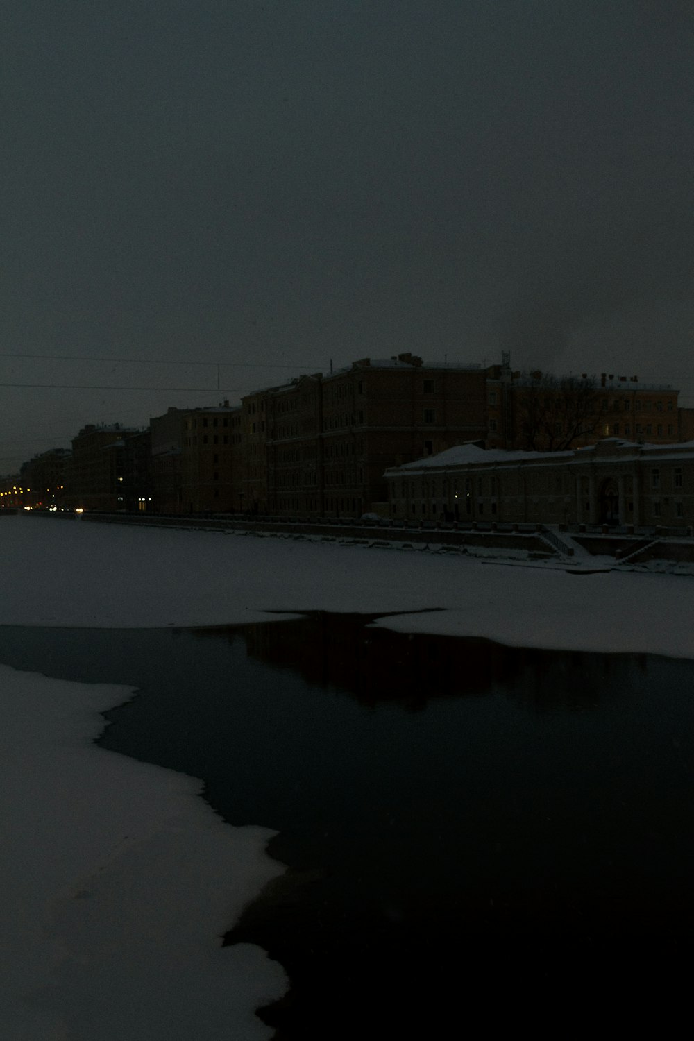 a snowy landscape with buildings and a body of water