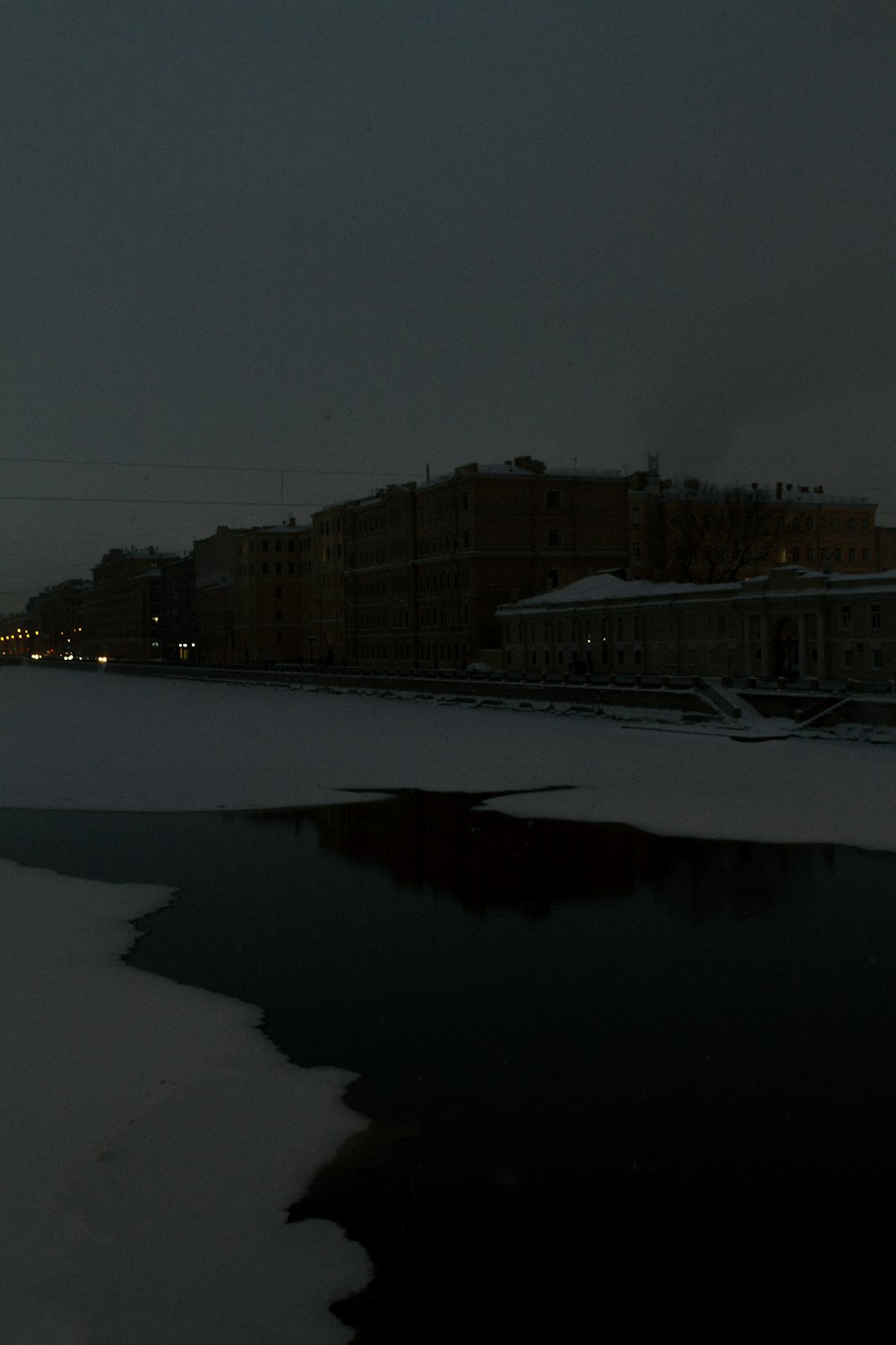 Un paisaje nevado con edificios y un cuerpo de agua