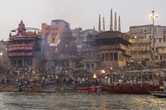 a group of boats floating on top of a river next to tall buildings