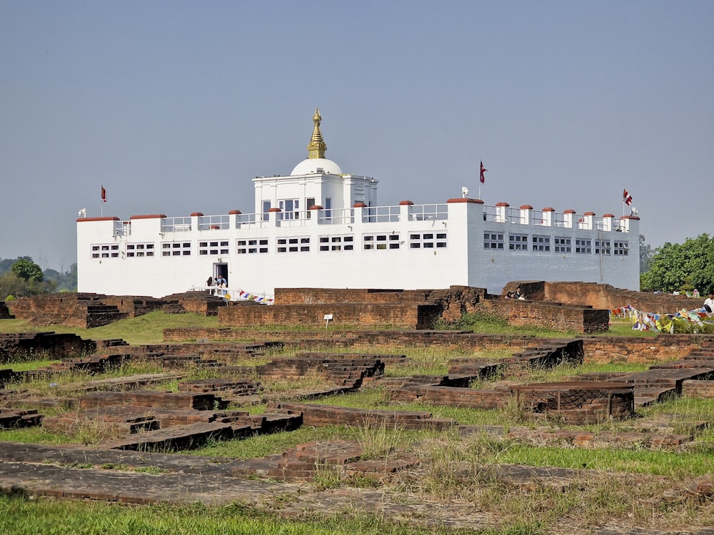 a large white building sitting on top of a lush green field