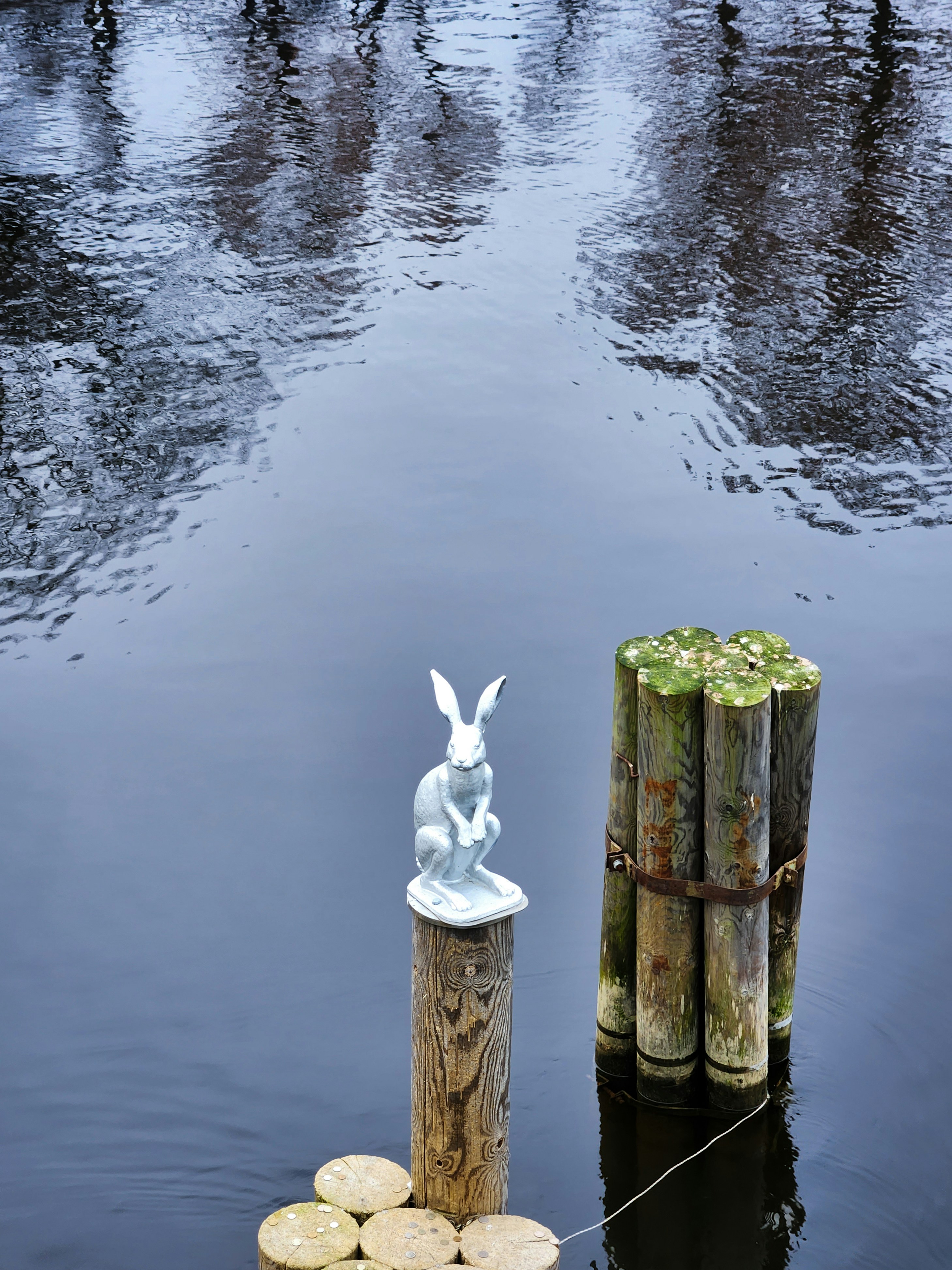 a statue of a rabbit sitting on top of a wooden post