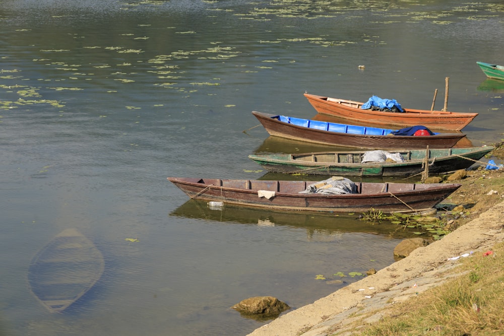 three canoes sitting on the shore of a lake