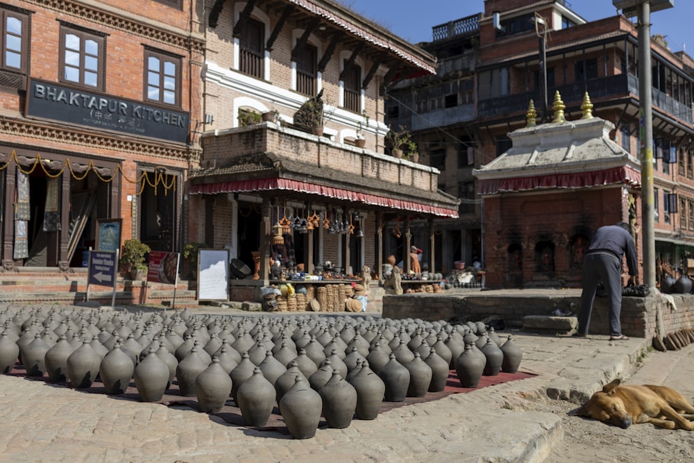a man standing in front of a building with lots of vases in front of