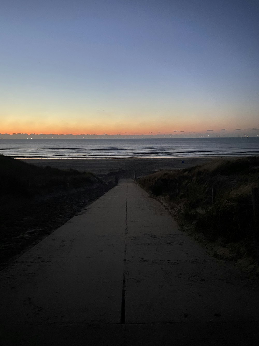 a long walkway leading to the ocean at sunset