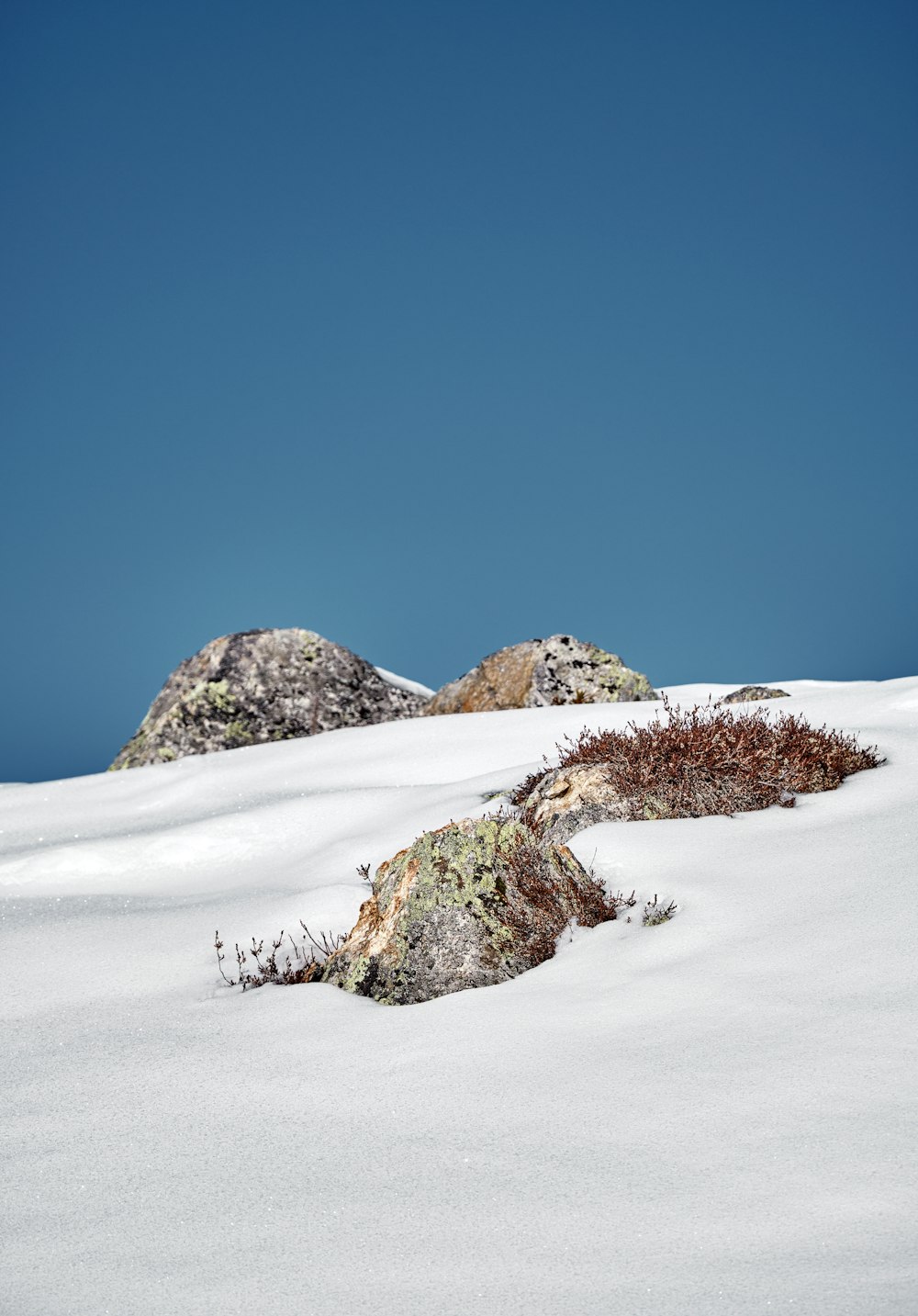 a snow covered hill with a few rocks on top of it