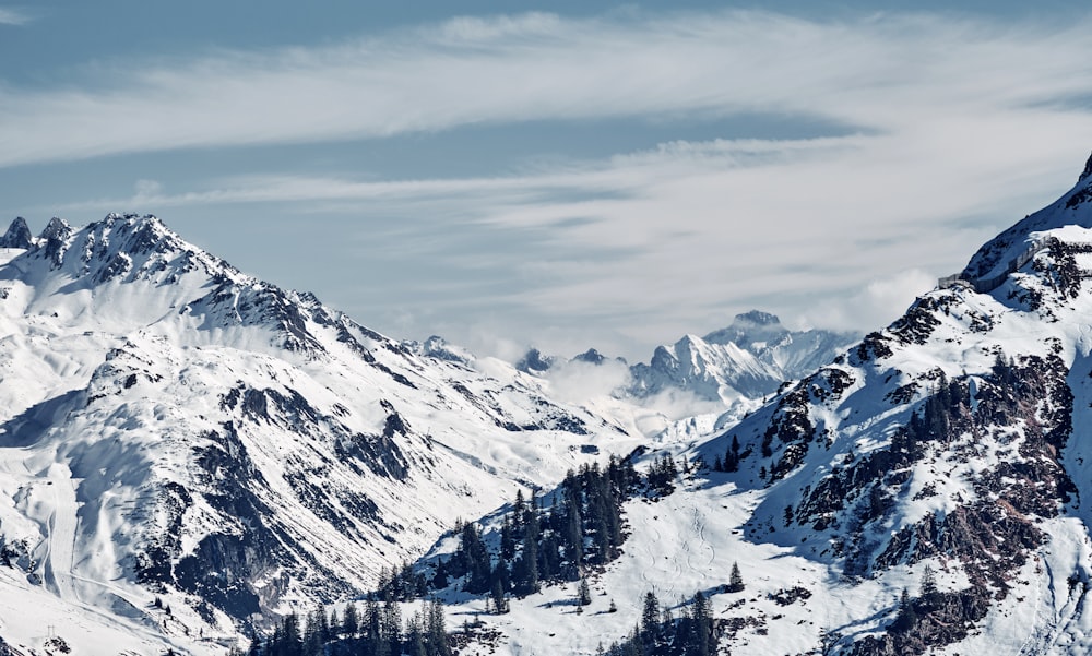 a mountain range covered in snow under a cloudy sky