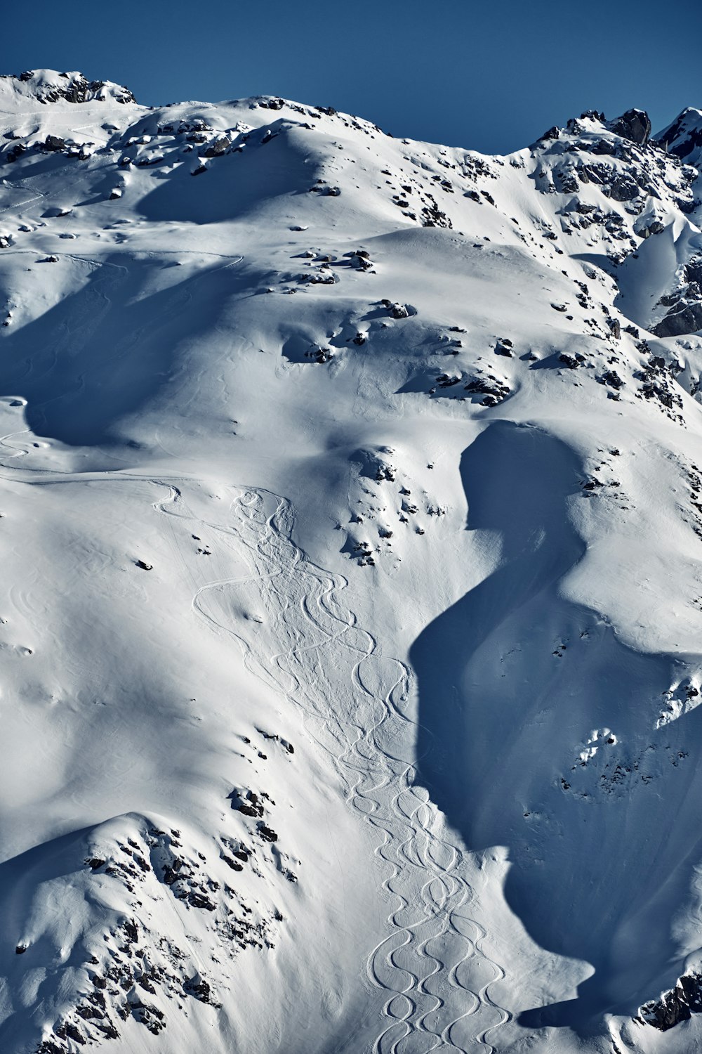 a mountain covered in snow with a blue sky in the background