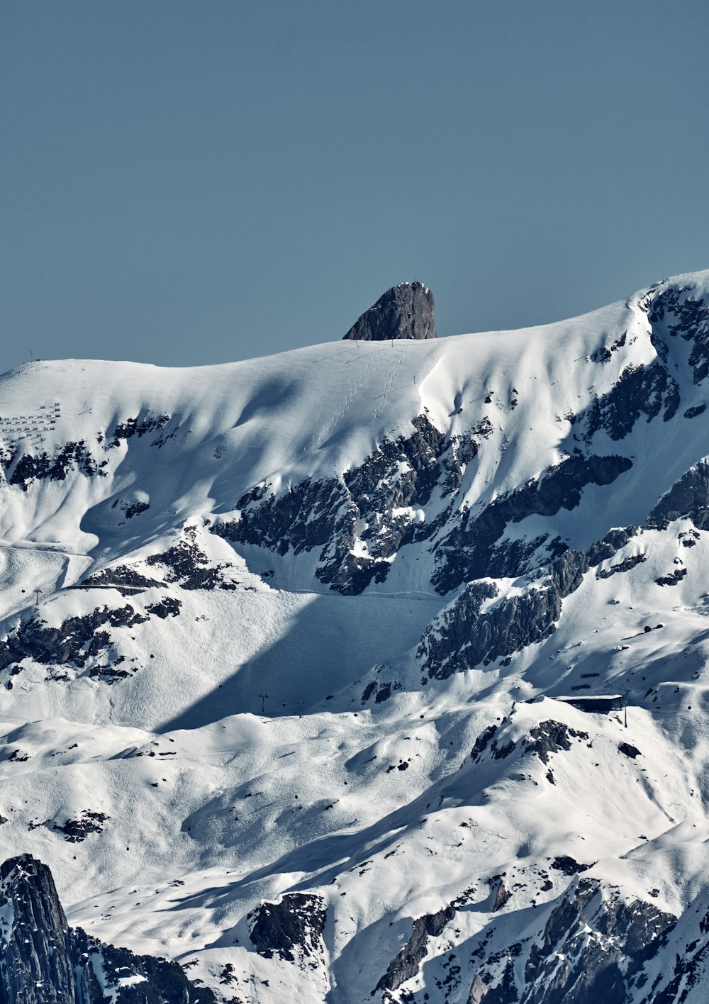 a large mountain covered in snow under a blue sky