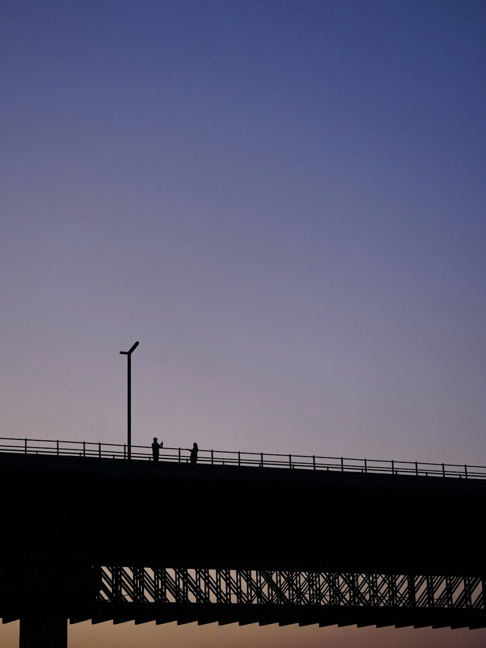 eine Person, die in der Dämmerung über eine Brücke geht