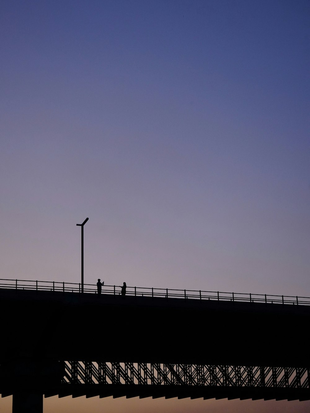 a person walking across a bridge at dusk