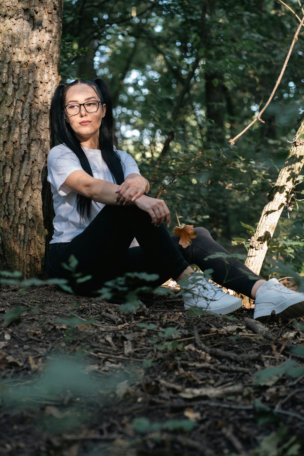 a woman sitting on the ground next to a tree