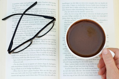 a person holding a cup of coffee in front of an open book