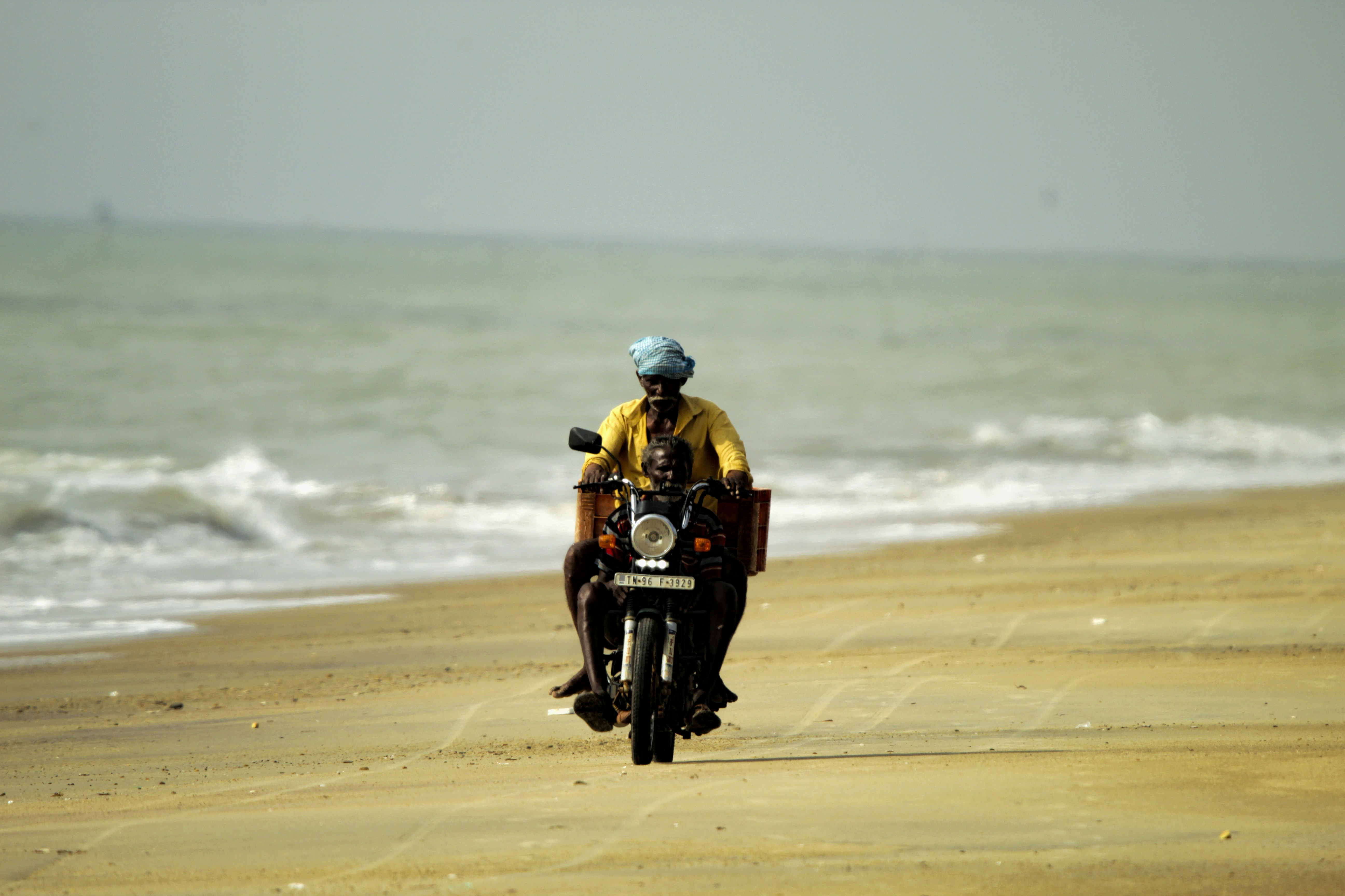 A man riding a motorcycle down a sandy beach photo – Free Street ...