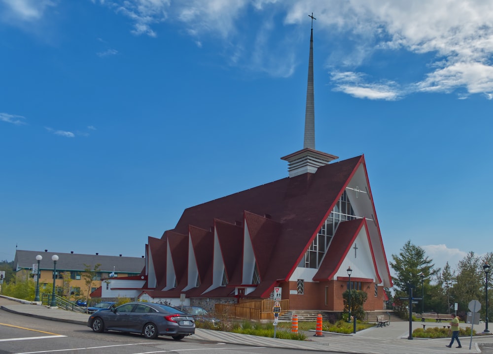 a church with a steeple and a car parked in front of it