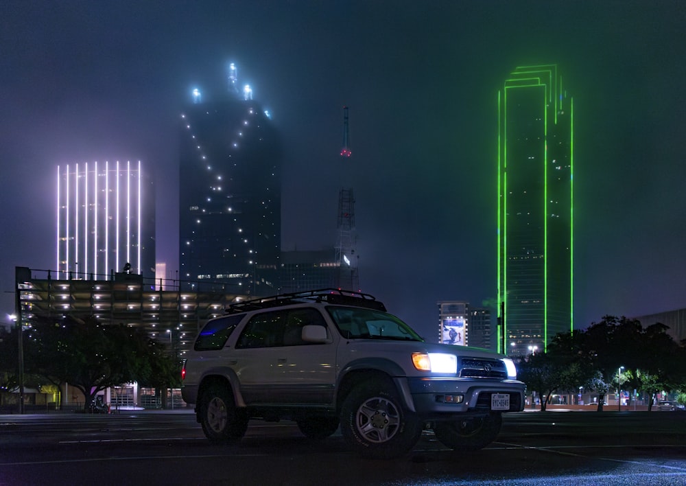 a white suv parked in front of a tall building