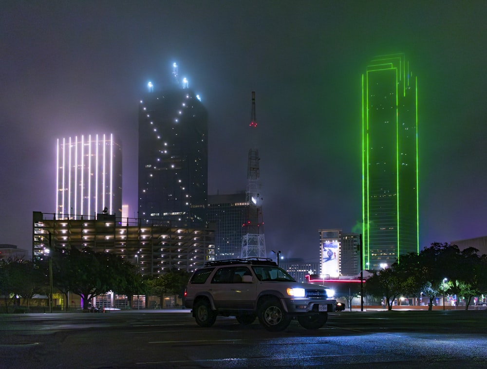 a car parked in front of a tall building at night