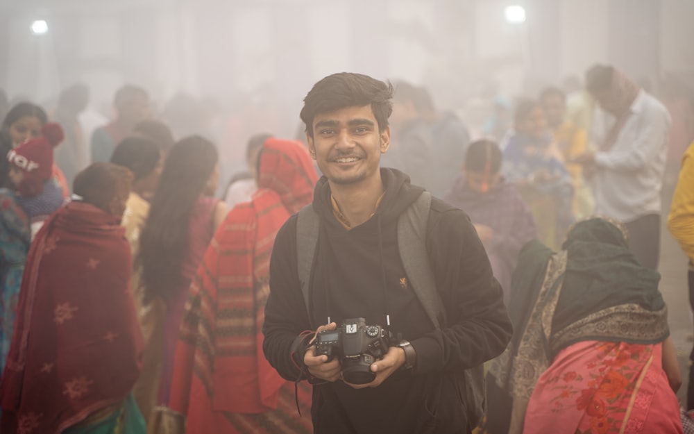a man holding a camera in front of a crowd of people