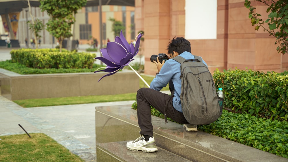 a man taking a picture of a purple flower