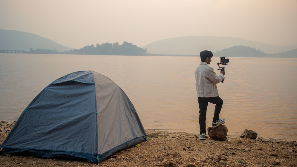 a man holding a camera next to a tent