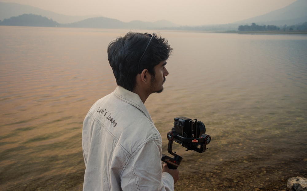 a man holding a camera near a body of water