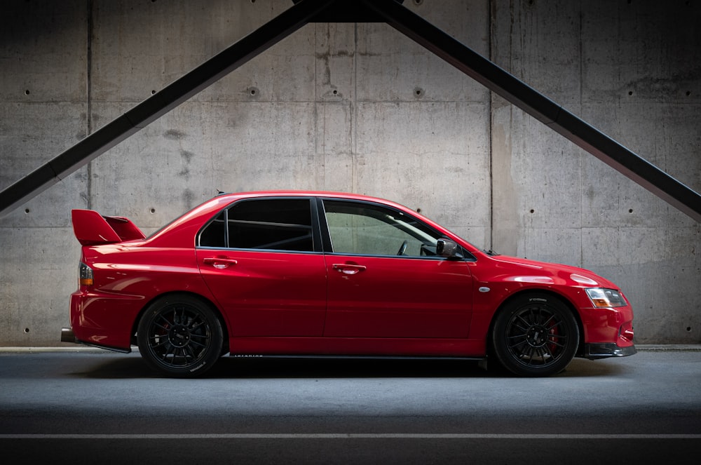 a red car parked in front of a concrete wall