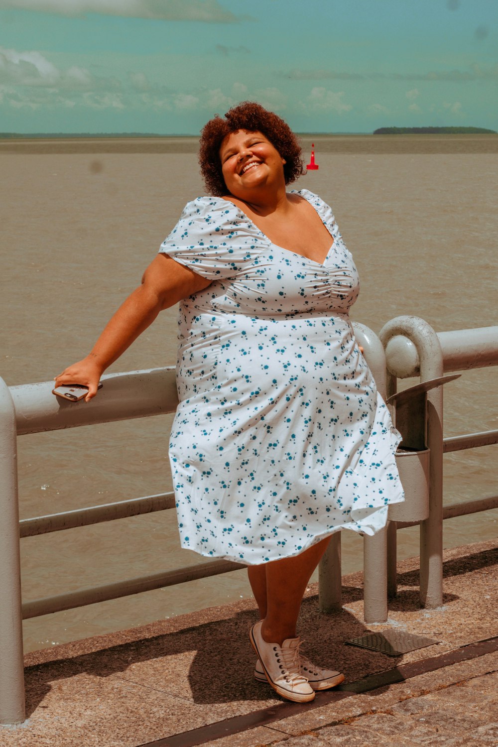 a woman leaning on a rail next to a body of water