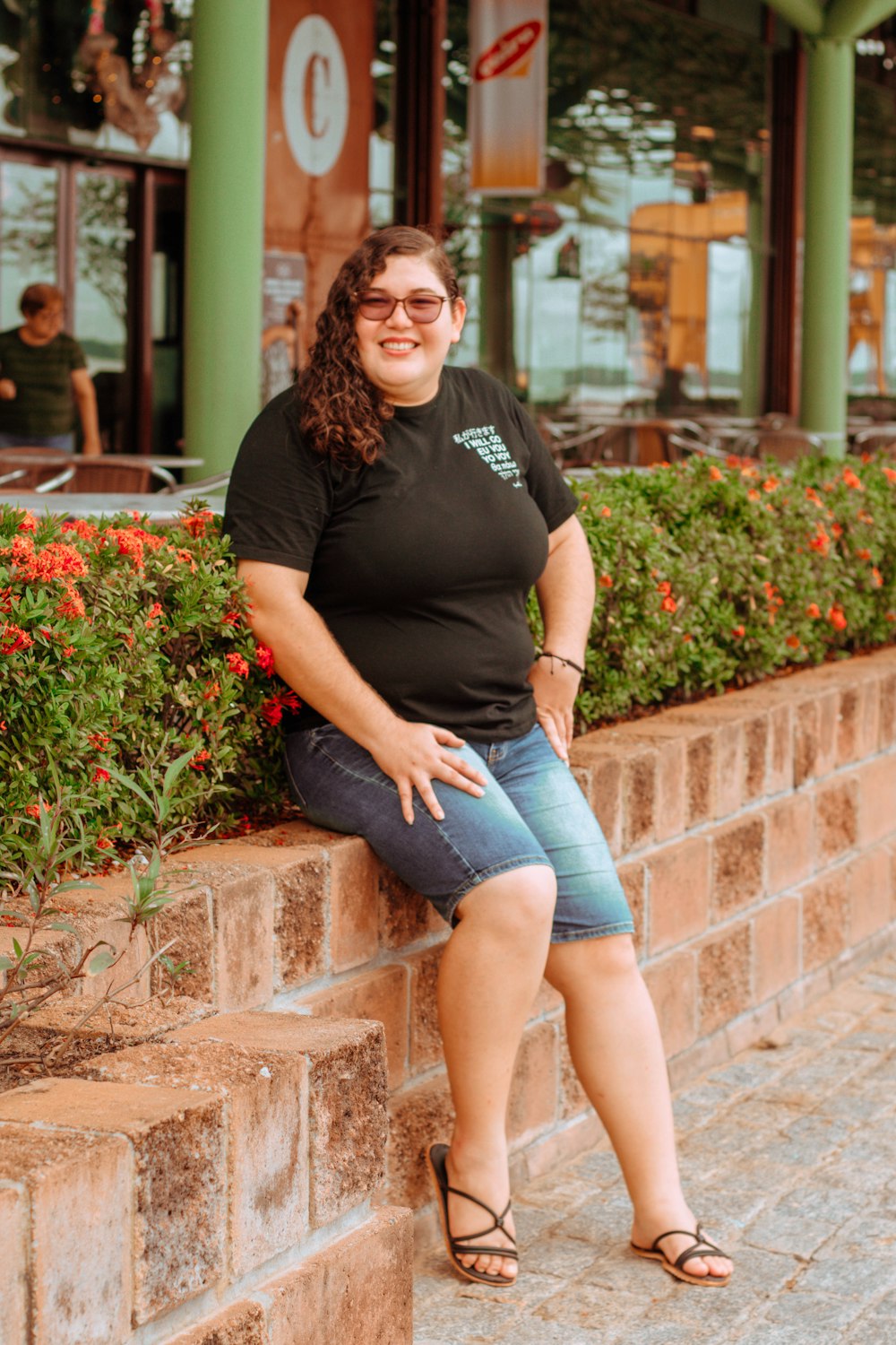 a woman sitting on a ledge in front of a building