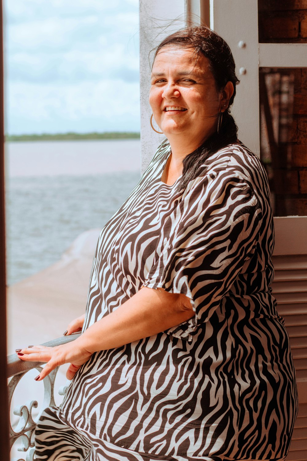 a woman standing by a window with a smile on her face