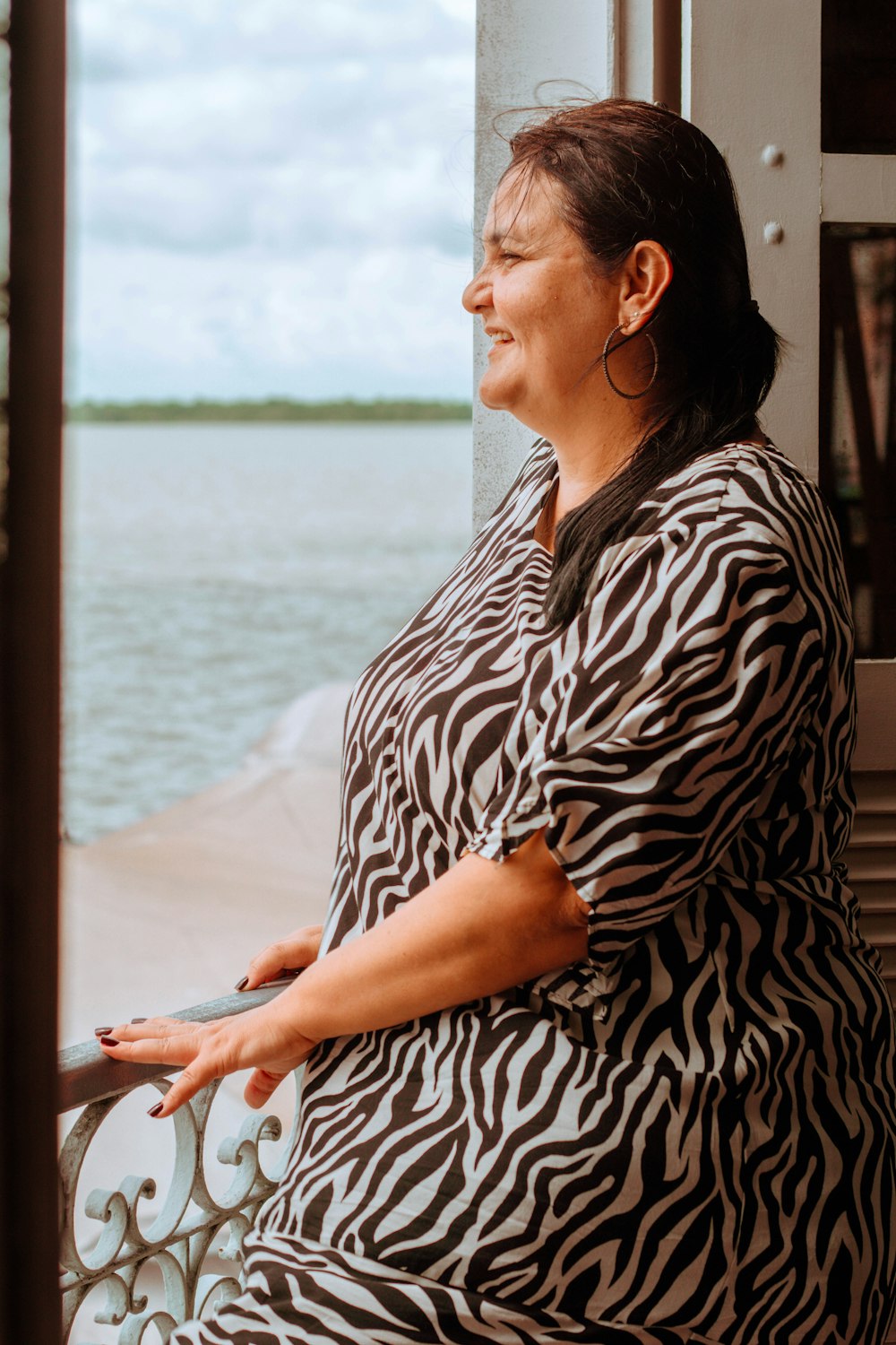 a woman standing on a balcony next to a body of water