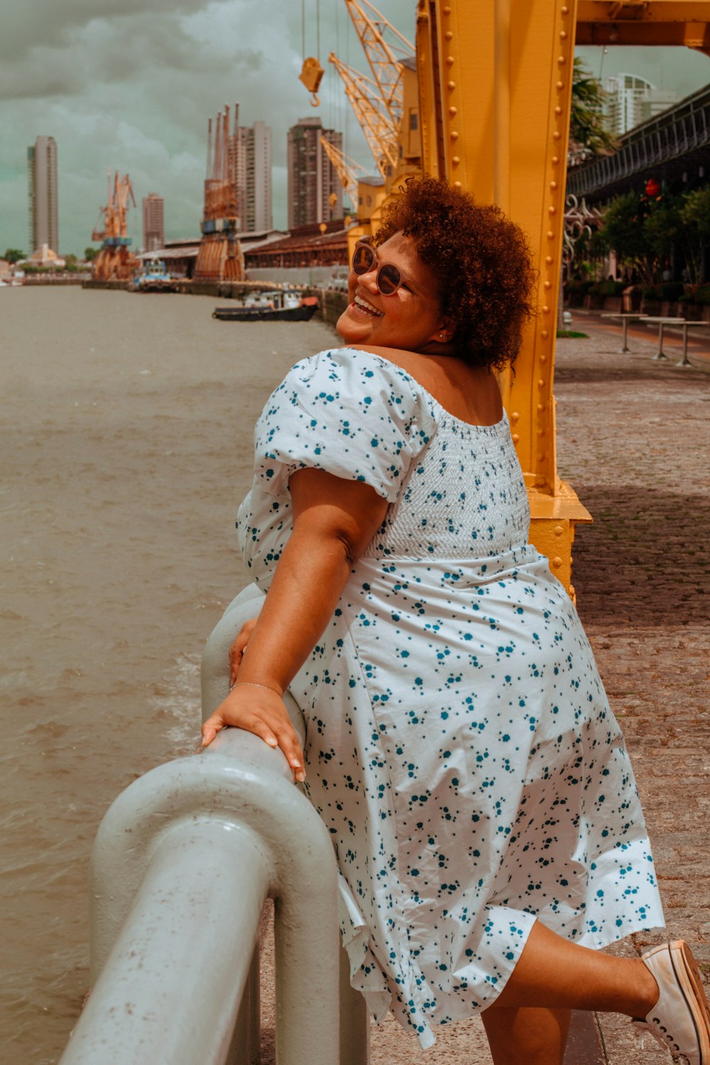 a woman leaning on a rail next to a body of water