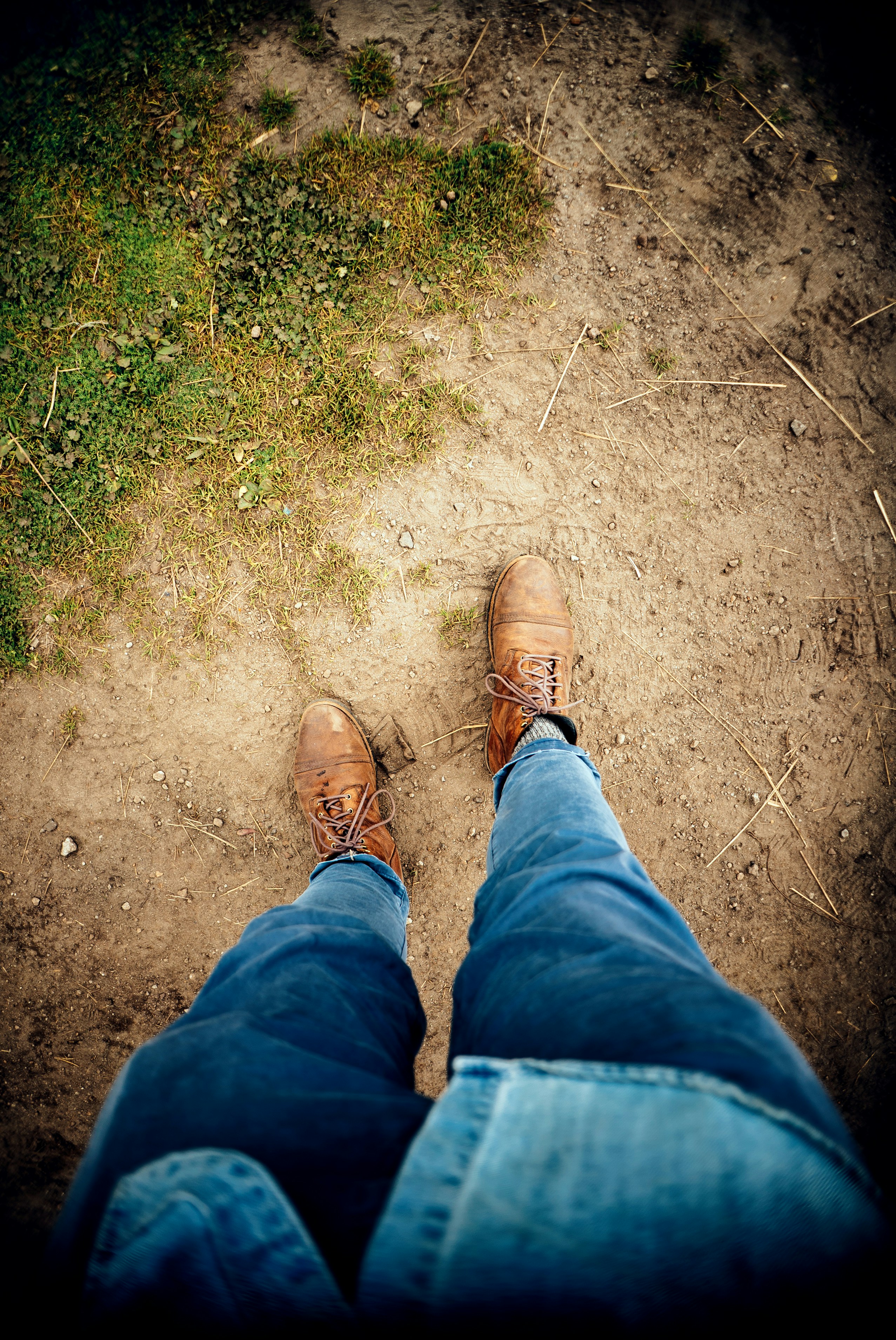 a person wearing brown shoes standing on a dirt road