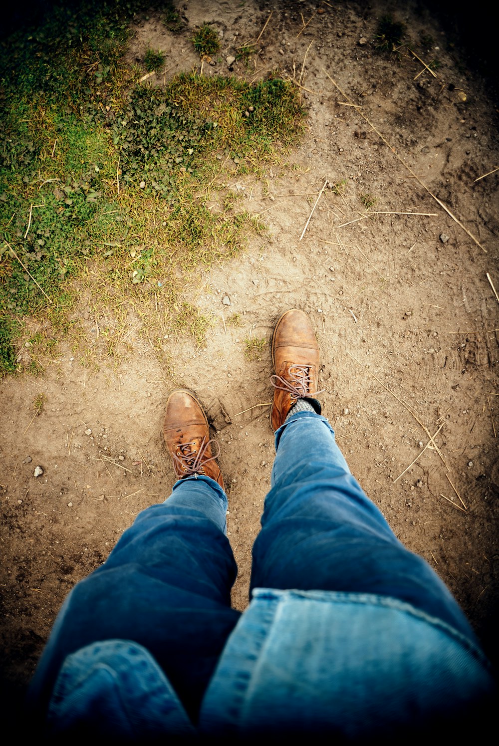 a person wearing brown shoes standing on a dirt road