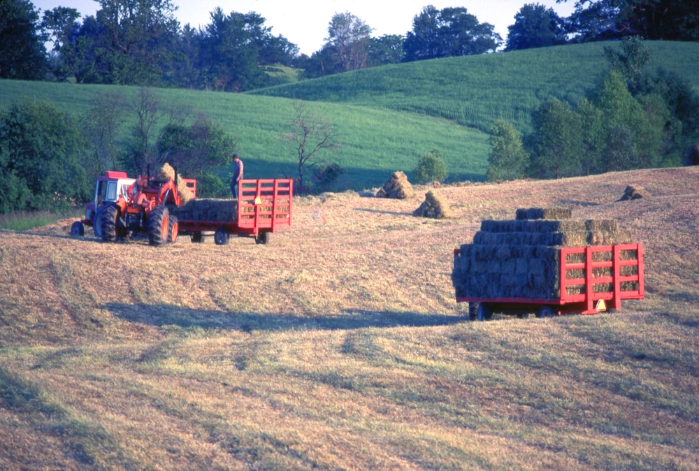 a tractor pulling a trailer of hay in a field