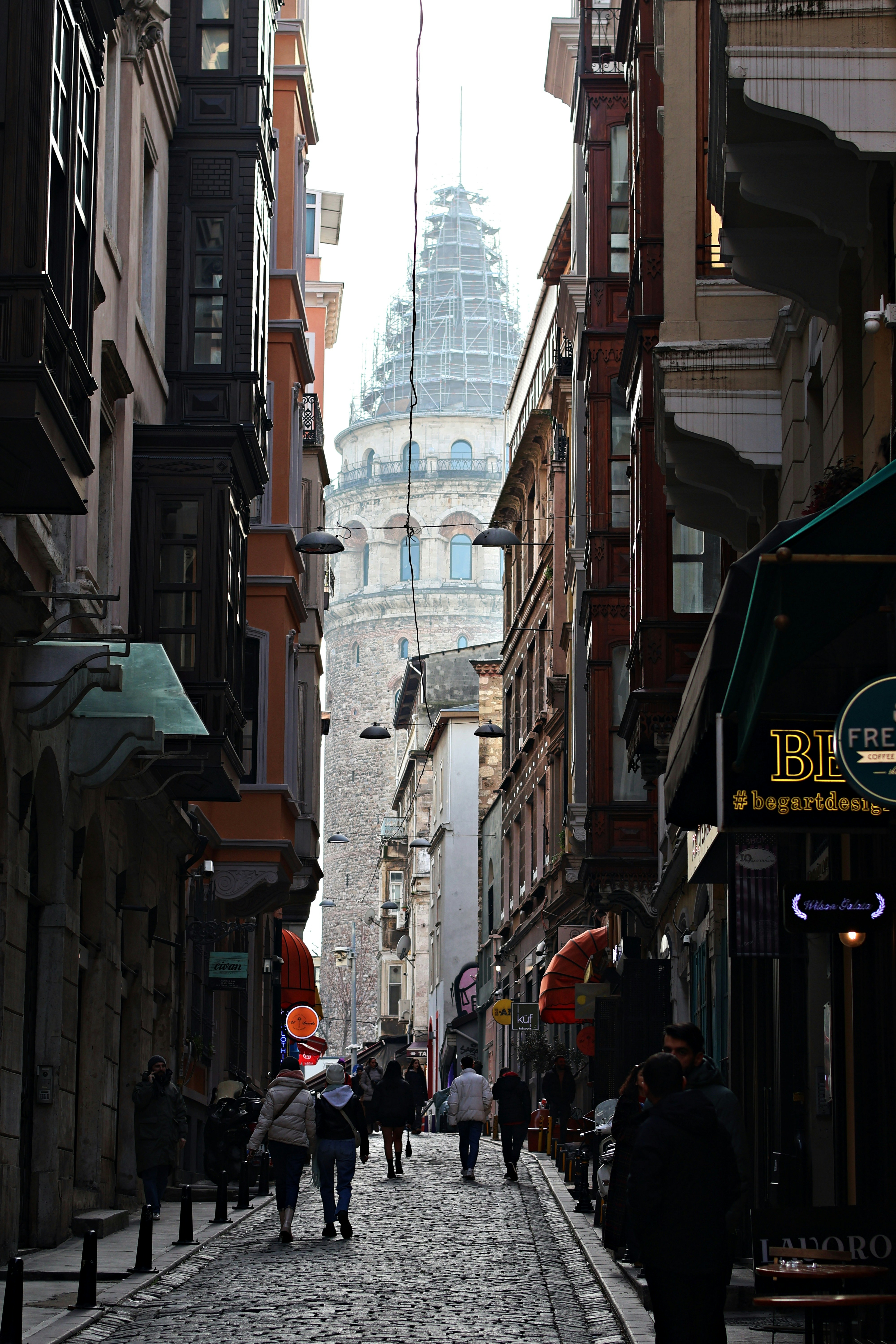 a group of people walking down a street next to tall buildings