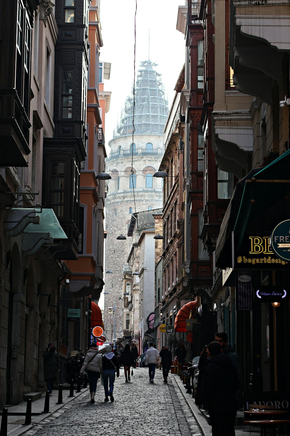 a group of people walking down a street next to tall buildings