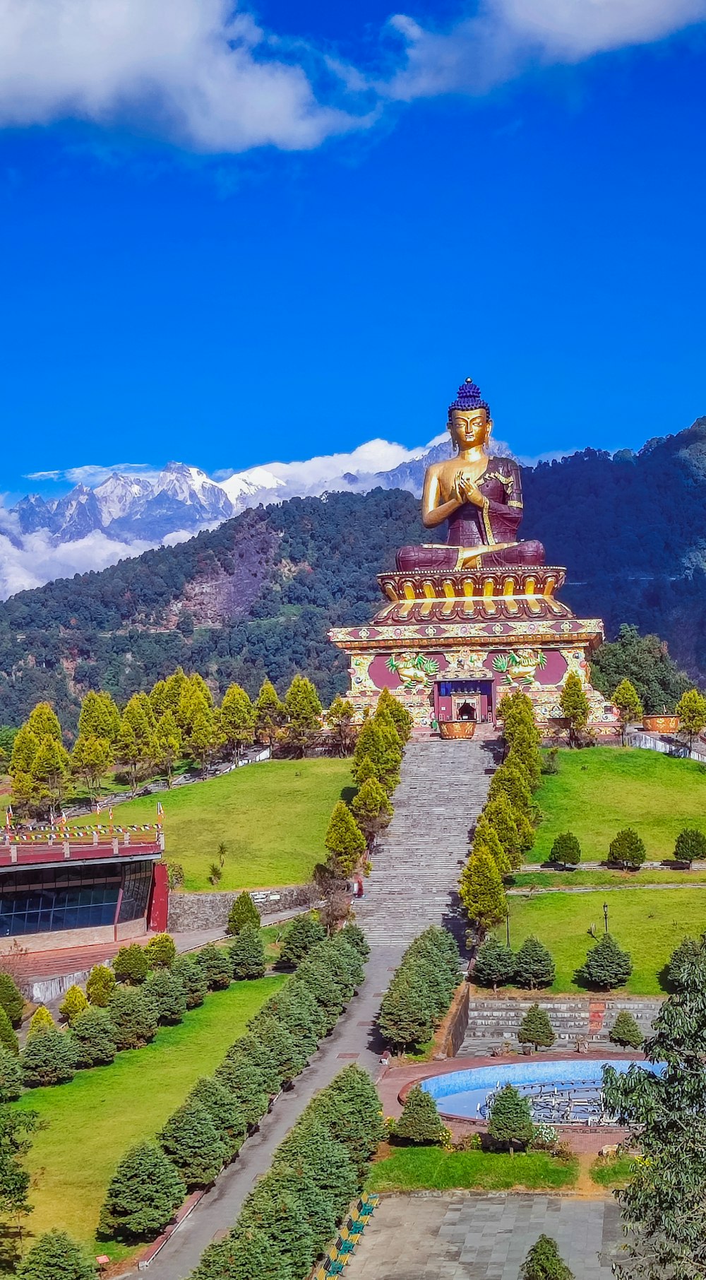 a large golden buddha statue sitting on top of a lush green field